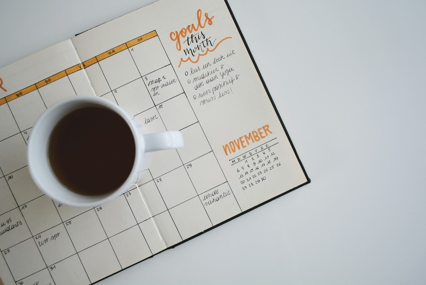 An open planner with a cup of coffee on the page.
