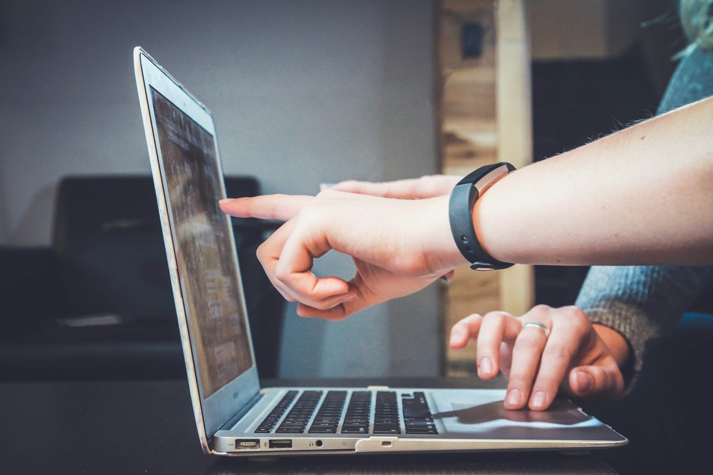 Hands at a laptop, one pointing at the screen.