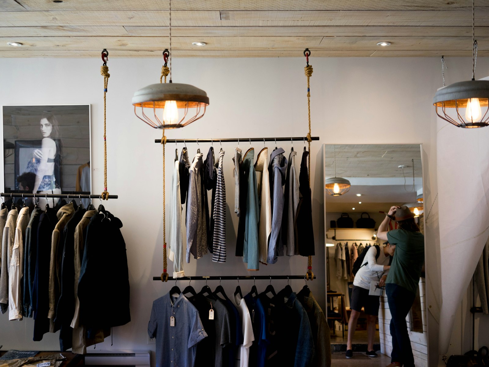 A clothing shop with racks and pendant lights.