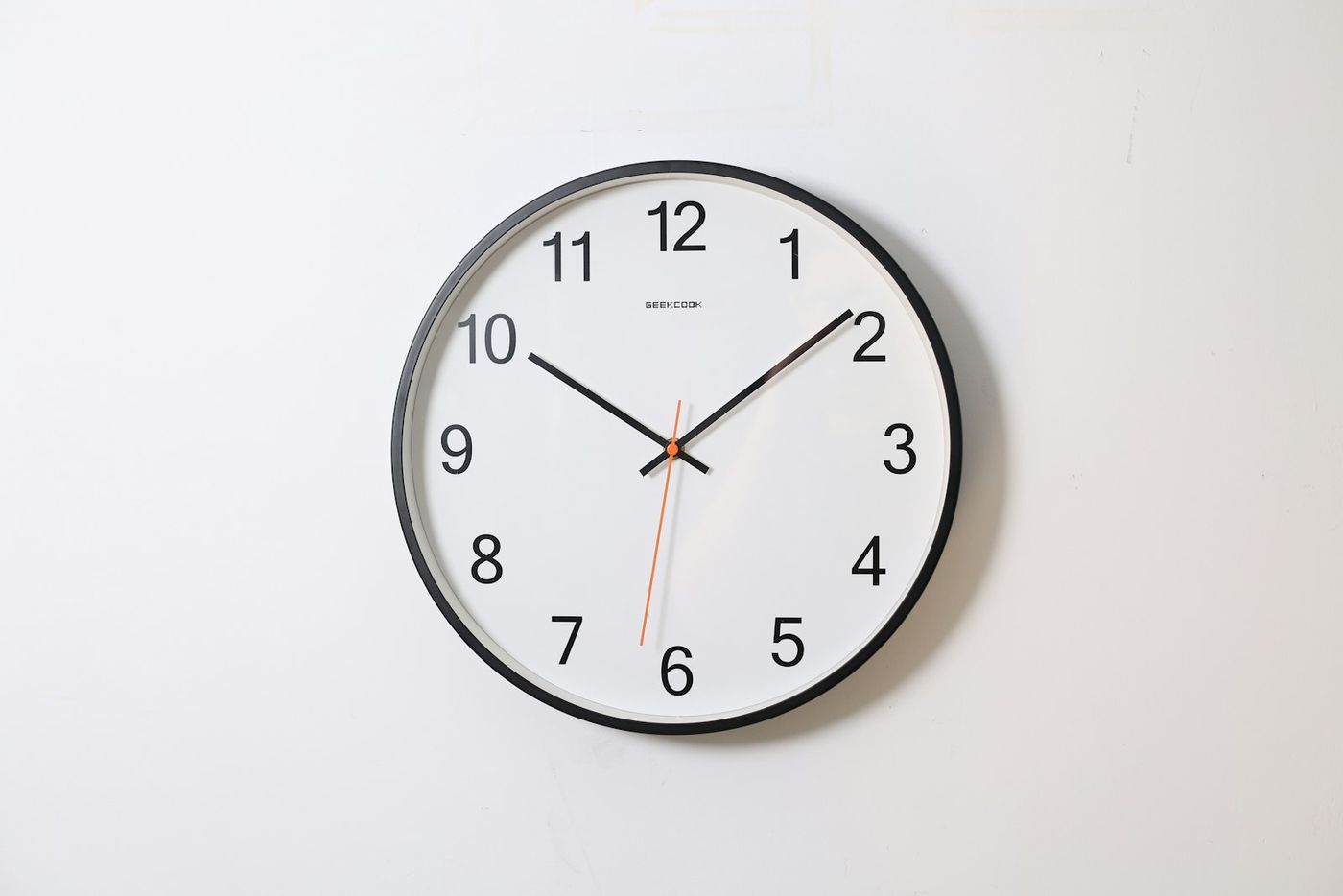 Round white wall clock with black hands on a plain white wall