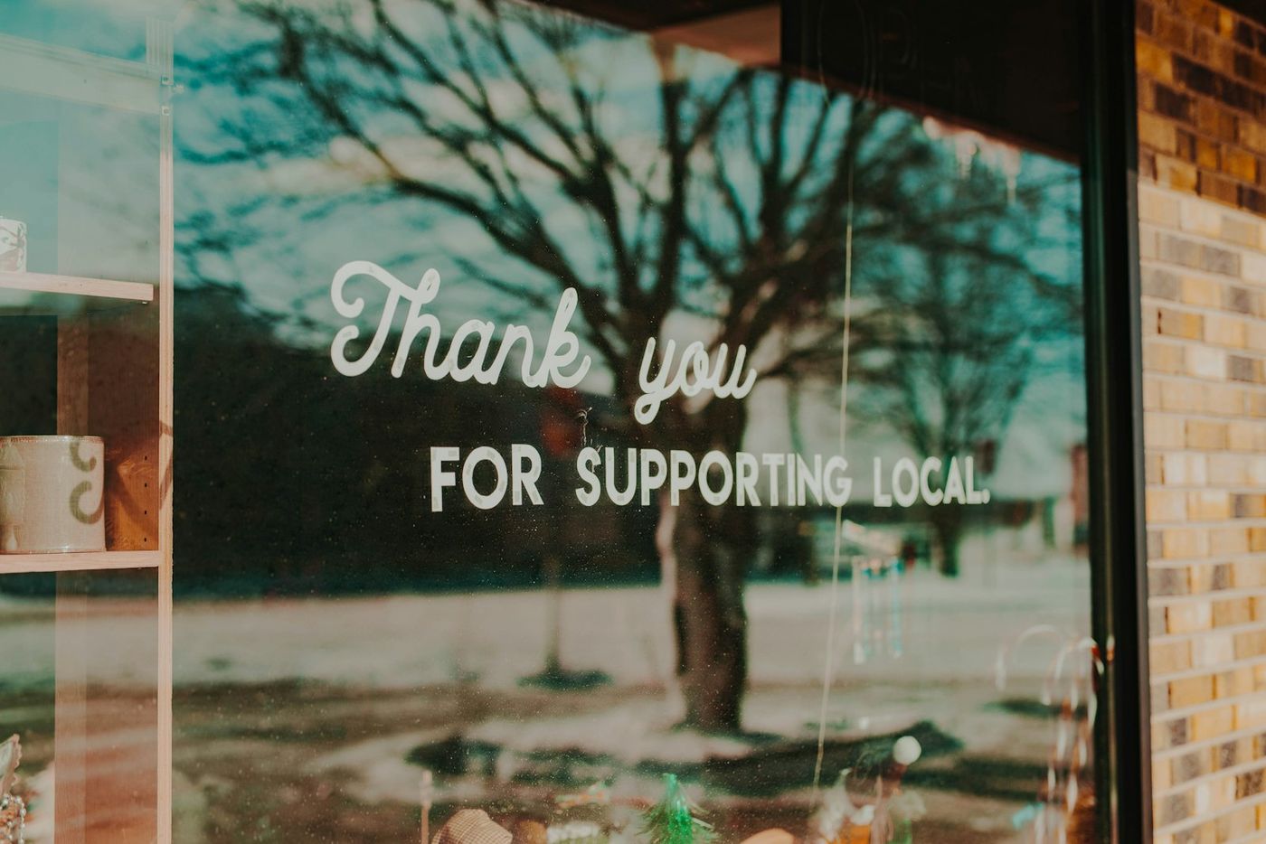 Shop window with a hand-painted sign thanking customers for supporting local businesses