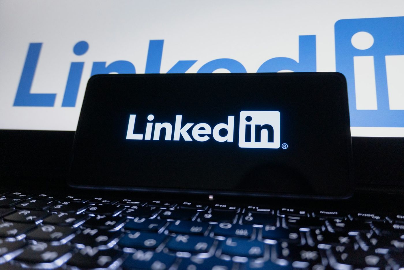Smartphone showing the LinkedIn logo in front of a laptop with LinkedIn branding