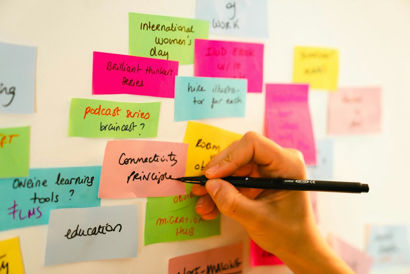 Hand writing on colorful sticky notes arranged on a whiteboard during planning