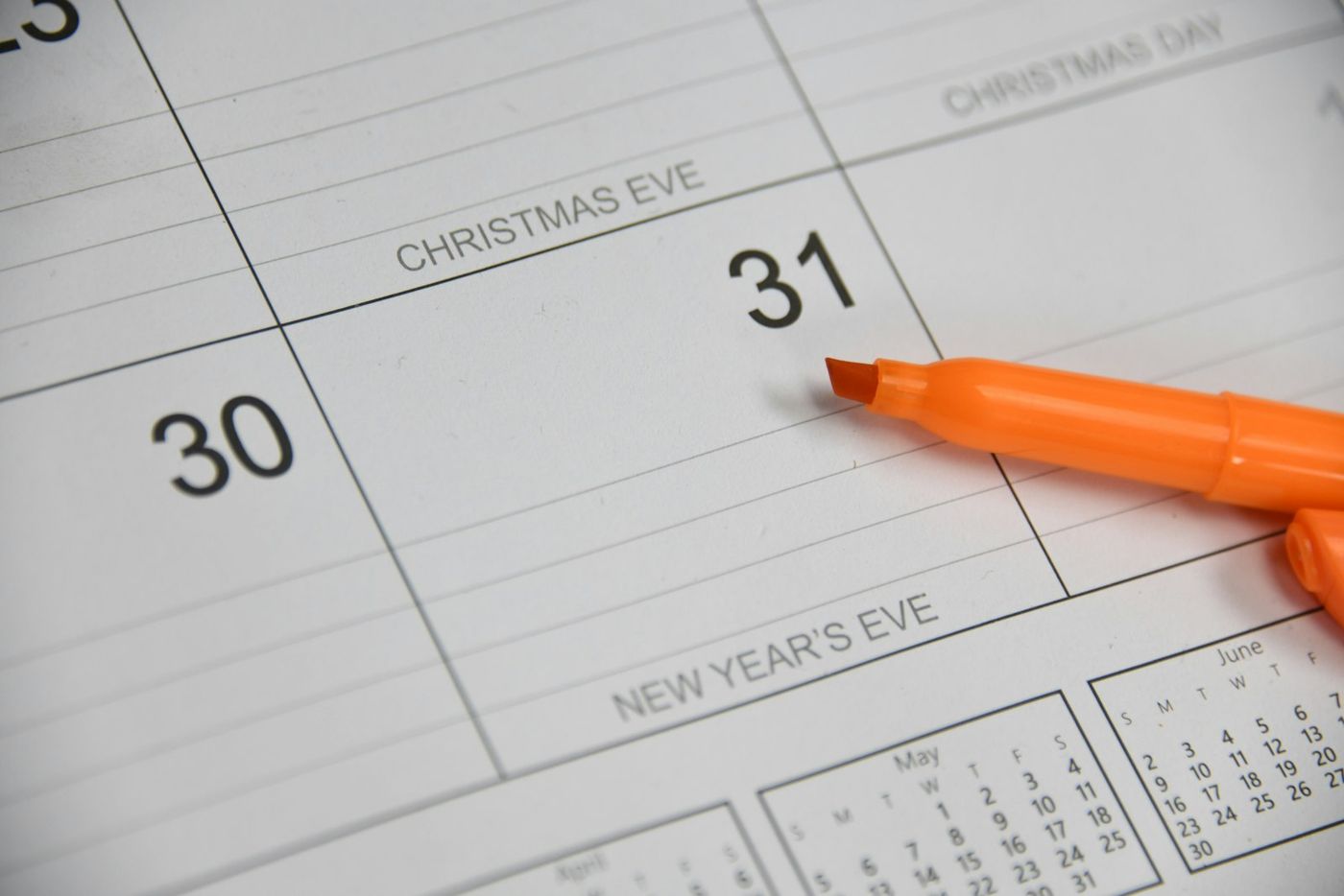 Orange marker resting on a paper calendar page near the end of the month